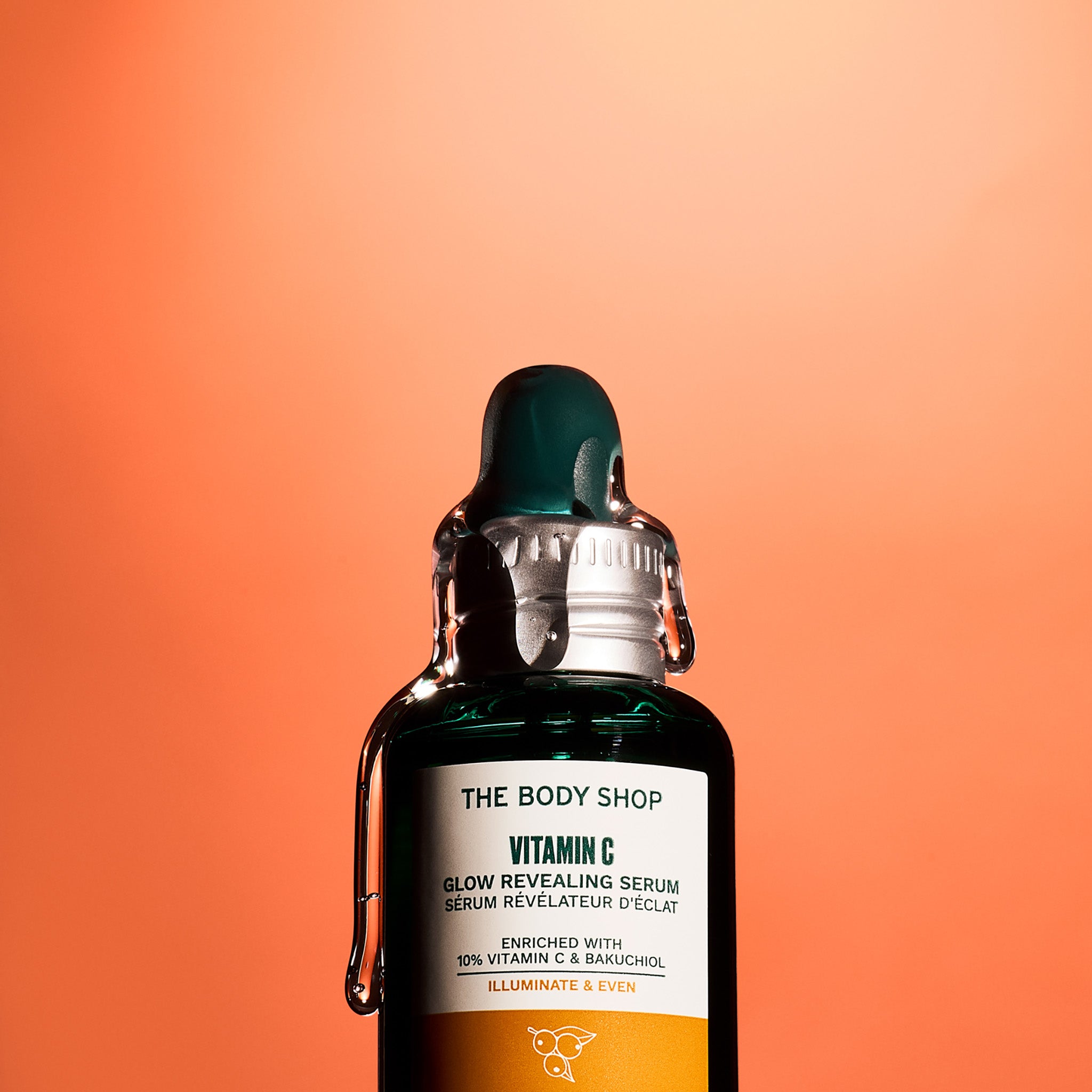 The Body Shop Vitamin C Glow Serum with serum dripping down the bottle from the cap.