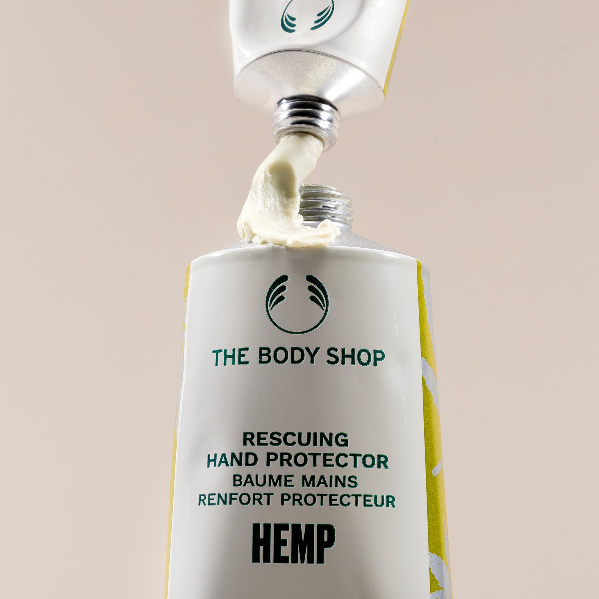 The Body Shop hand protector with cream being applied on a beige background