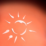White sun-shaped object using The Body Shop skin defence, on an orange background